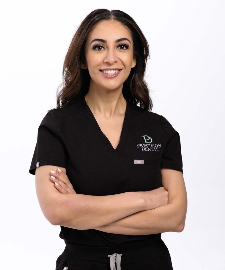 A photo of Dr. Nazanin Ghazisharif crossing her arms and wearing a black scrubs with a logo of 'PRECISION DENTAL' in a plain white background.