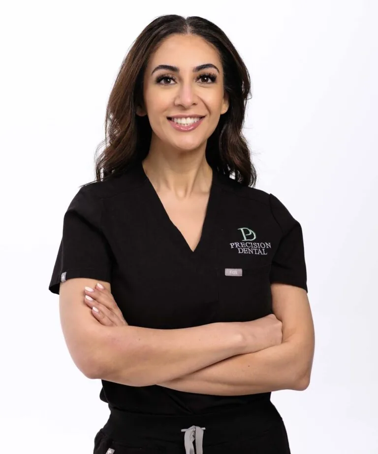 A photo of Dr. Nazanin Ghazisharif crossing her arms and wearing a black scrubs with a logo of 'PRECISION DENTAL' in a plain white background.